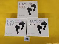 Three sealed boxes of Haylou GT7 True Wireless Earbuds arranged on yellow surface.