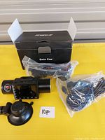 IIWEY dash cam with lens, LCD screen, suction cup mount, power cable, and original box all displayed on yellow surface.