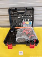 Photo showing the carrying case with drill accessories including bits, screws, plastic anchors, and charger, all organized inside.