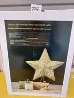 Photo of boxed Christmas star tree topper with LED lights and spring base. Box shows product image and specifications.