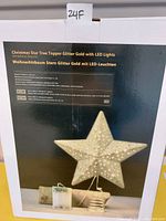 Photo of a boxed gold star Christmas tree topper glittered with LED lights and spring base. Box shows product image and details.