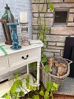 Overview of the set showing white table with candle holders, wooden lantern, firewood basket and leaf tiles.