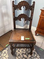 Full view of the solid carved wood vintage chair showing front with carved backrest, seat, and legs.
