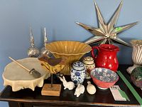 Complete view of lot items including drum, fruit bowl, pitcher, jars, figurines, wooden bird, and star mirror.