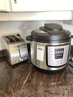Side view of Instant Pot IP-LUX pressure cooker next to Moulinex stainless steel toaster on kitchen counter.