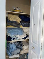 Photo showing linen cupboard with folded towels, sheets, and storage bags on shelves