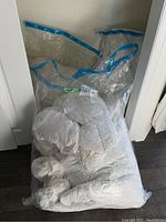 Overall view of vacuum packed duvets and pillows in storage bags on floor.