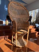 Full view of rattan caned peacock lounge armchair showing the woven pattern and shaped wide back, armrests, and base.