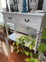 Front angle view of white painted wooden sideboard showing two drawers with black metal handles and bottom shelf.