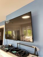 Front view of the 48 inch Sony flat screen TV mounted on a wall with accessories below it.