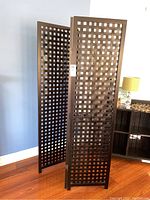 Full view of three-panel privacy screen standing on a hardwood floor near blue wall.