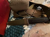 Vintage army belt with attached canteen and knife in scabbard laid on a crocheted mat.