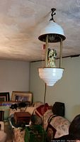 White metal and glass ceiling-hung lamp with a figurine inside.