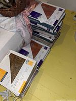 13 boxes stacked showing two different Styleselections self-stick vinyl tile designs in their original packaging.