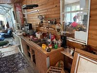 Overview of kitchen counter with multiple appliances and household items including crock pot, coffee maker, hanging rack, and more.