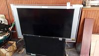 Two Roku TVs side by side, larger LG Bravia (45 inch) with silver frame and smaller black Emerson (31 inch) in front