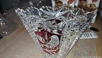 Lead crystal vase showing detailed cut star patterns and ruby red panels with bird engraving.