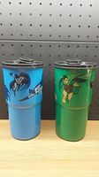 Two plastic cups standing side by side, one blue with Batman graphics and one green with Robin graphics, showing the design and overall condition.