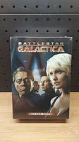Front cover of sealed Battlestar Galactica Season 3 DVD box set showing main characters.