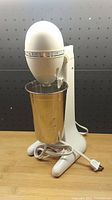 Front view of the white Hamilton Beach Drink Master Classic blender with metal mixing cup, showing power cord and base.