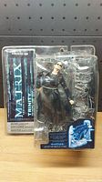 Photo of new Matrix Trinity action figure in original blister packaging with visible crack on plastic cover.