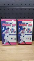 Photo of two sealed MLB Showdown 2000 card game boxes on wooden surface against black pegboard background.