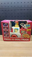 Front view of 1986 Unimax Press-N-Roll toy truck in original box showing toy and box graphics.