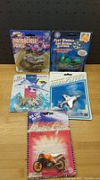 Lot of five small diecast collectible vehicles including one motorcycle and four planes in blister pack packaging.