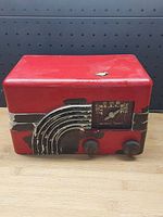 Front view vintage Northern Electric red radio with decorative grille, tuning dial, and knobs.