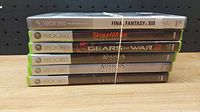 Stack of six Xbox 360 video game cases, titles clearly visible.
