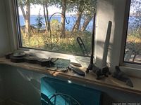 Wide shot of lot on window sill showing soapstone seal, metal dog paper roll holder, antique reading glasses with wood case, and barometer with thermometer on wooden base.