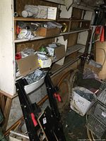 Wide view of wooden shelving containing boxes of electrical supplies, hardware, and various workshop items in a cluttered space.
