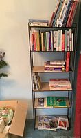 Full view of metal framed faux wood shelf filled with books of various types.
