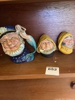 Three nautical ceramic pieces: Bosson head sailor pitcher with mermaid, hand-painted Bosson head figurine in yellow hood, Royal Doulton Old Salt pitcher