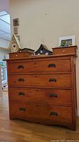 Front view of rustic pine dresser with four large drawers, each with metal cup handles and two small drawers with round knobs on top.