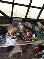 A collection of various electrical parts and hardware loosely placed on a wooden table including light fixtures, cables, and boxes.