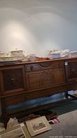 Front view of walnut buffet showing carved panels, brass knobs, two drawers, drop-down door and lower rail.