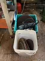 Green plastic bin with electric grinder and several grinding and cutting discs stacked inside.