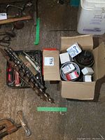 Box containing various hole saws in boxes and loose, also drill bits in a bin, displayed on the floor