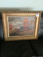 Frontal view of the framed oil painting showing a stormy autumn landscape with farmhouse and trees.