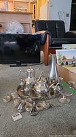 Full view of pewter serving set arranged on carpet including tray, tea and coffee pots, cream and sugar, salt and pepper shakers, candleholder, napkin rings