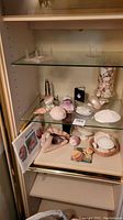 Shelf with large shells, a few standing displays, two books leaning, and some smaller shells scattered.