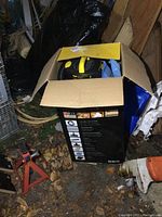Stanley vacuum in opened cardboard box placed on ground with packing and surrounding environment visible.