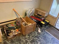 Wide view showing wooden boxes and plastic toolbox containing assorted tools and hardware on floor.