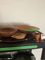 Wide view of the wooden bowls, coin holder, tray and egg cups arranged on a black surface.