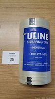 Front label view of one clear Uline strapping tape roll with blue Uline branding on a wood table.