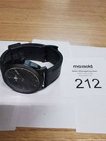 Black Fossil watch laid flat showing the leather strap and watch face with dial and markers visible.