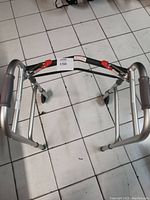 Top view of folded walker showing red locking levers and rubber hand grips, aluminum frame.
