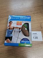 Photo of the boxed Gaiam Cork Handled Resistance Cord workout kit showing front packaging with a woman using the resistance cord. Box labeled Light/Medium and includes DVD with 30 workouts.