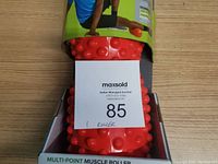 Photo showing a red Gaiam Multi-Point Muscle Roller in its packaging, with maxsold lot card on top.